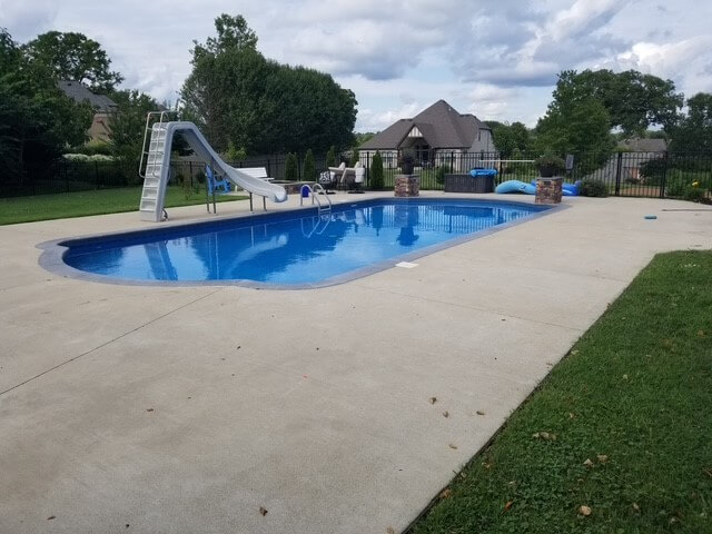 Inground pool with a natural stone waterfall and clear blue water in Tennessee.